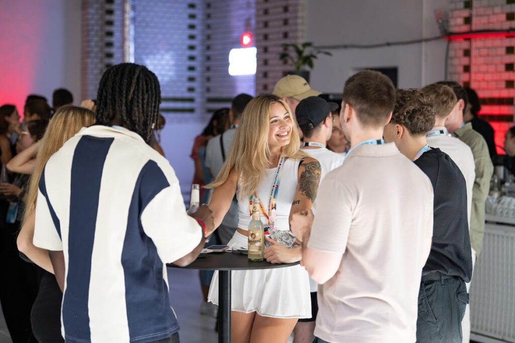 Lena Westermann bei einem Networking-Event, im weißen Outfit an einem Stehtisch im Gespräch mit anderen Gästen.
